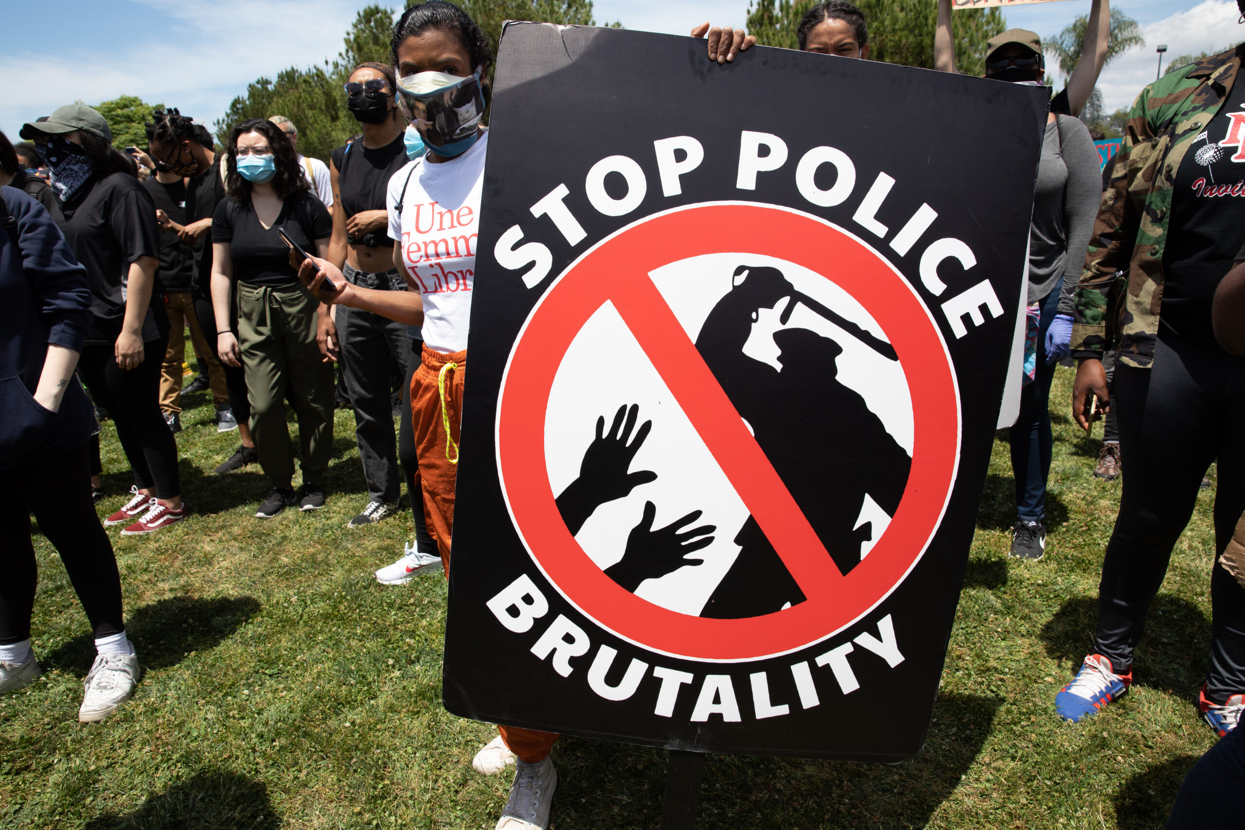 Woman at a protest holding a sign saying "stop police brutality"